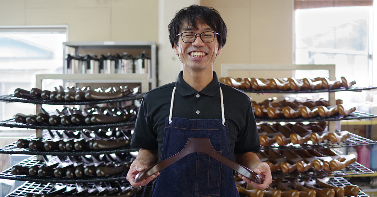 NAKATA HANGER artisan holding a finished wooden hanger