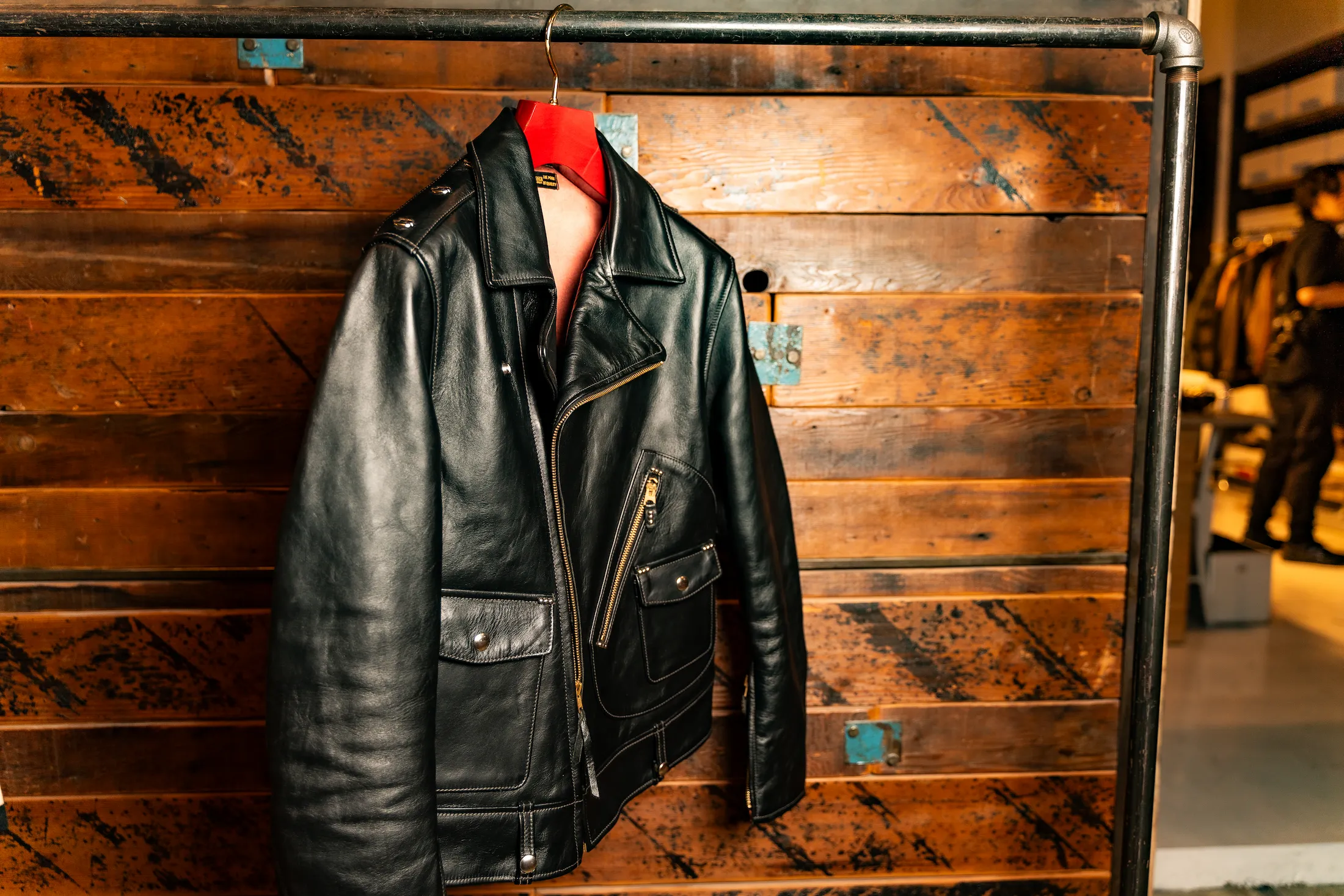 赤い木製ハンガーにかけられた、黒いレザージャケット