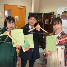 卒業袴とブレザー姿でハンガーと書類を持つ生徒の写真