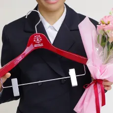 卒業式で赤いハンガーと花束を持つ卒業生の写真