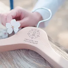 ロゴが刻印された木製ハンガーと桜の花びら